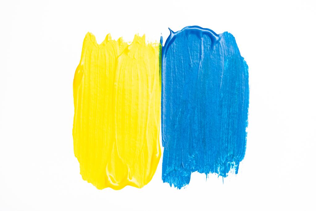 vista superior de pinceladas de tinta azul e amarela coloridas abstratas no fundo branco - Foto, Imagem