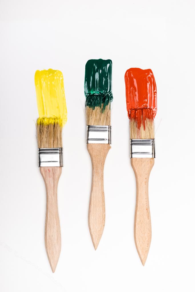 top view of paintbrushes near colorful paint brushstrokes on white background - Photo, Image