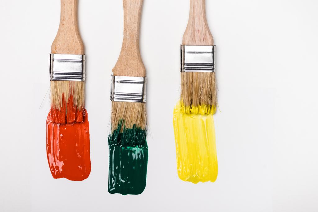 Renkli boya fırçalarının yanında beyaz arkaplanda fırça darbelerinin üst görünümü - Fotoğraf, Görsel