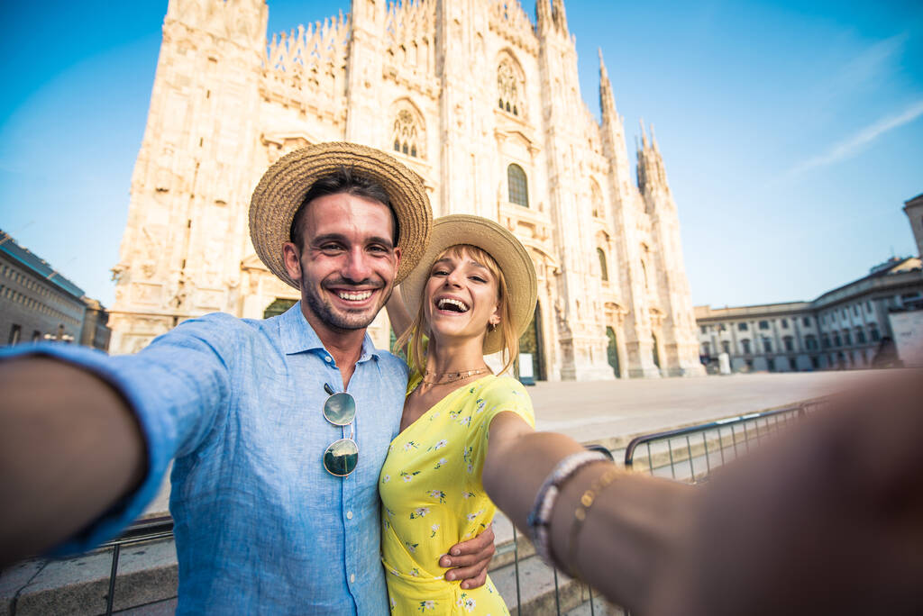 Εικόνα ενός ευτυχισμένου ζευγαριού σε διακοπές. Νεαρός άνδρας και γυναίκα βγάζουν selfie στο Μιλάνο κοντά στον καθεδρικό ναό Duomo - Φωτογραφία, εικόνα