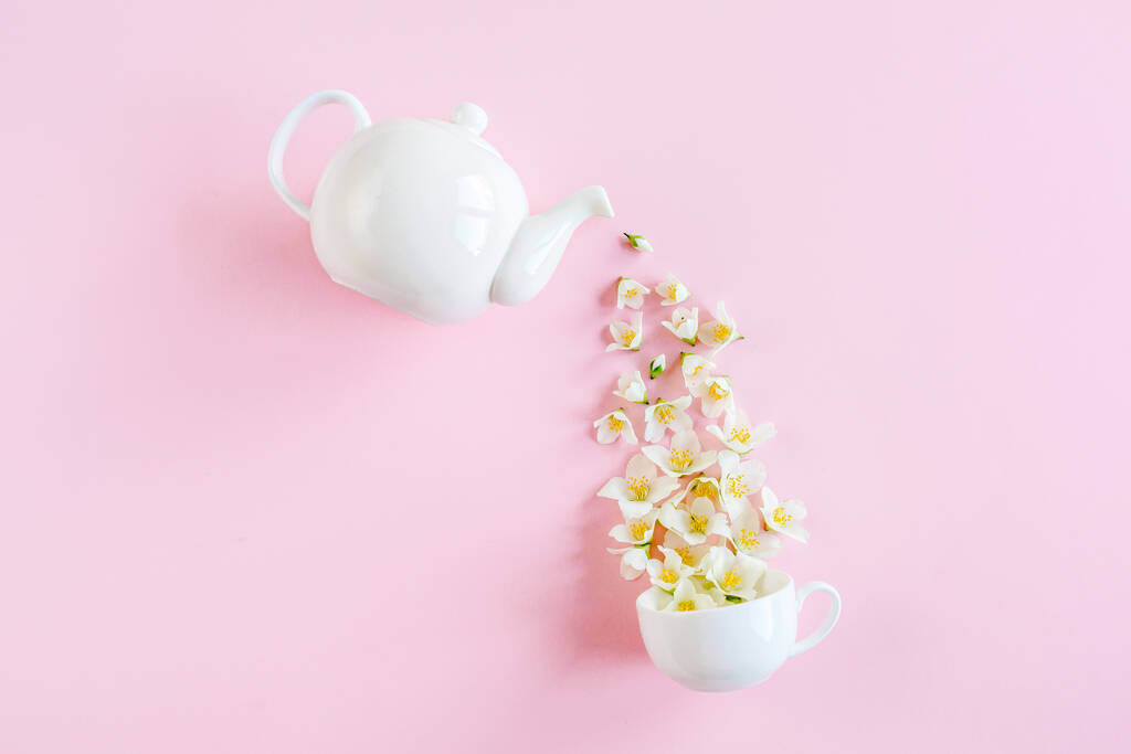 Creative layout of teapot and tea Cup with Jasmine flowers on a pink background. Jasmine tea. - Photo, Image