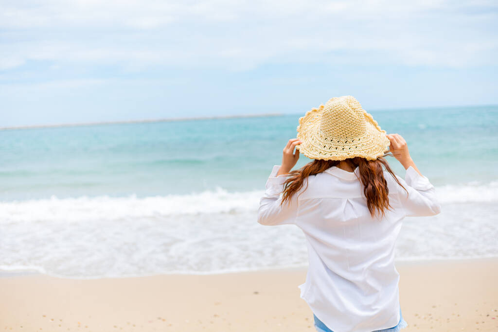 Kumsalda güneş şapkası takan genç bir kadın. yaz, tatiller, tatil, seyahat kavramı - Fotoğraf, Görsel