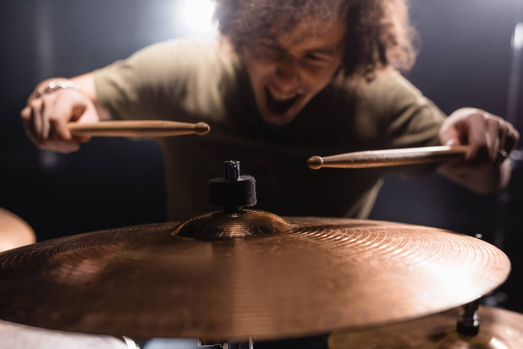 Metal cymbal with blurred drummer holding drumsticks background - Photo, Image