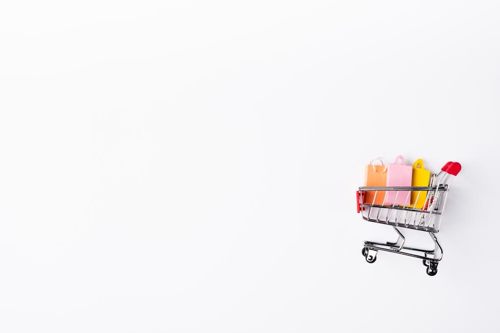 Vista superior de coloridas bolsas de compras de juguetes en el carro sobre fondo blanco - Foto, imagen