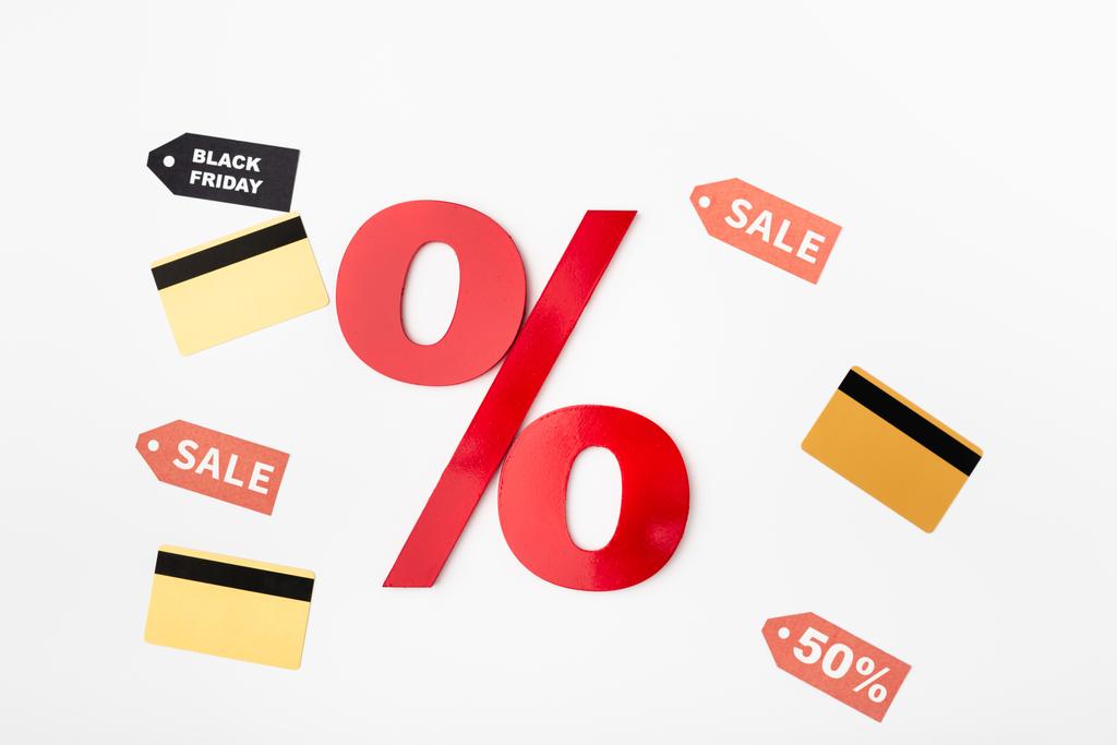 Visão superior do sinal de porcentagem perto de cartões de crédito e etiquetas de preço com letras de venda em fundo branco - Foto, Imagem