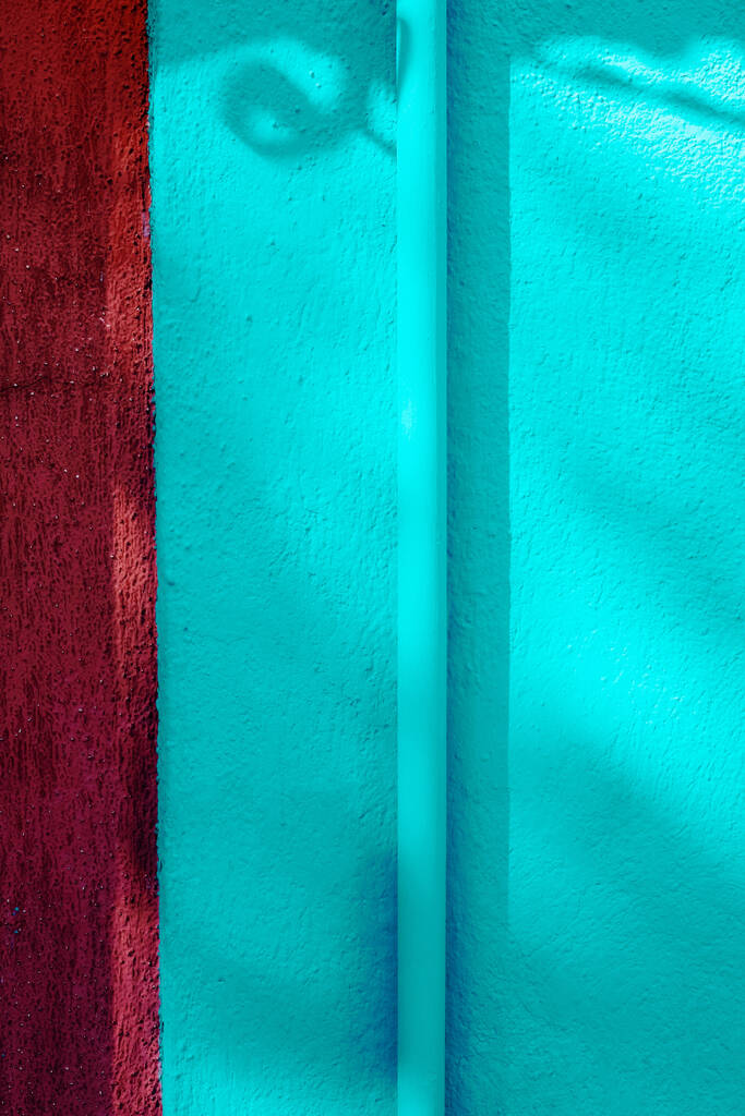 Egy függőleges lövés egy cső a falon festett fényes kék a napfény alatt - Fotó, kép