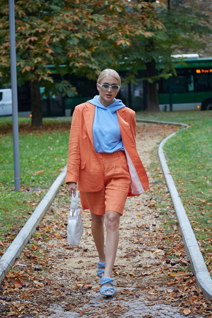 MILÁN, ITALIA - 25 DE SEPTIEMBRE DE 2020: Mujer con chaqueta naranja y sudadera con capucha azul pálido caminando antes del desfile de moda Sportmax, Milan Fashion Week street style - Foto, Imagen