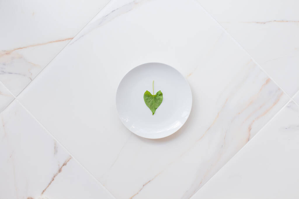 Концепция диеты и похудения, пост и очищение организма. Пустая белая тарелка на белом мраморном столе. Очистите организм зелеными продуктами - Фото, изображение