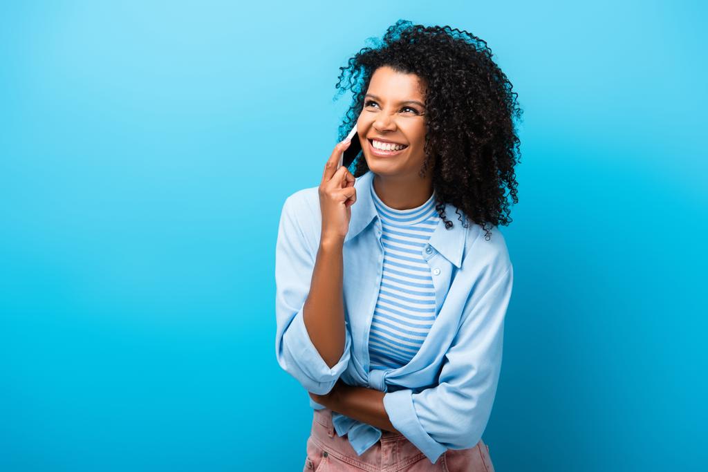 onnellinen afrikkalainen amerikkalainen nainen puhuu älypuhelimella sinisellä - Valokuva, kuva