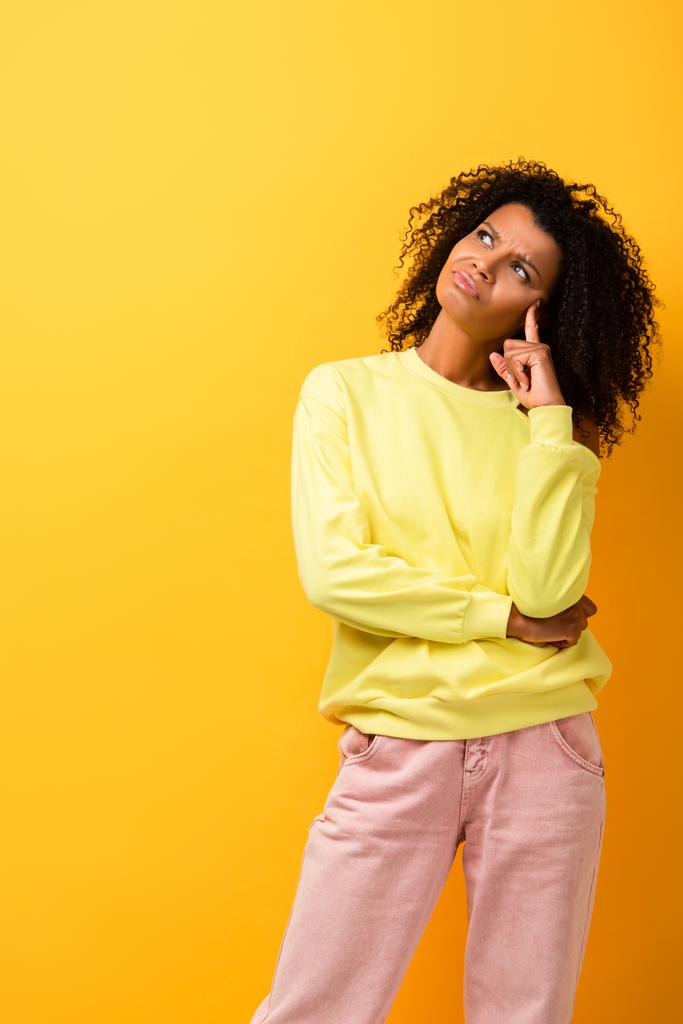 mulher afro-americana pensativa olhando embora enquanto pensa no amarelo - Foto, Imagem
