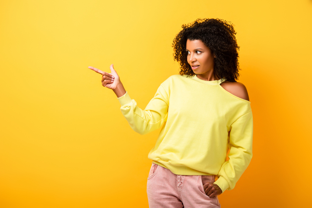 surprised african american woman pointing with finger on yellow - Photo, Image