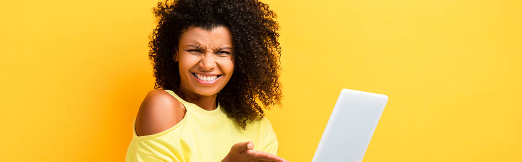 скептически настроенная африканская американка, указывающая рукой на цифровой планшет на желтом, баннер - Фото, изображение