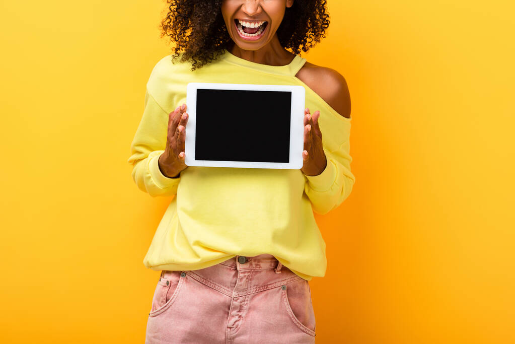 przycięty widok afrykańskiej amerykanki trzymającej tabletkę cyfrową z białym ekranem na żółtym - Zdjęcie, obraz
