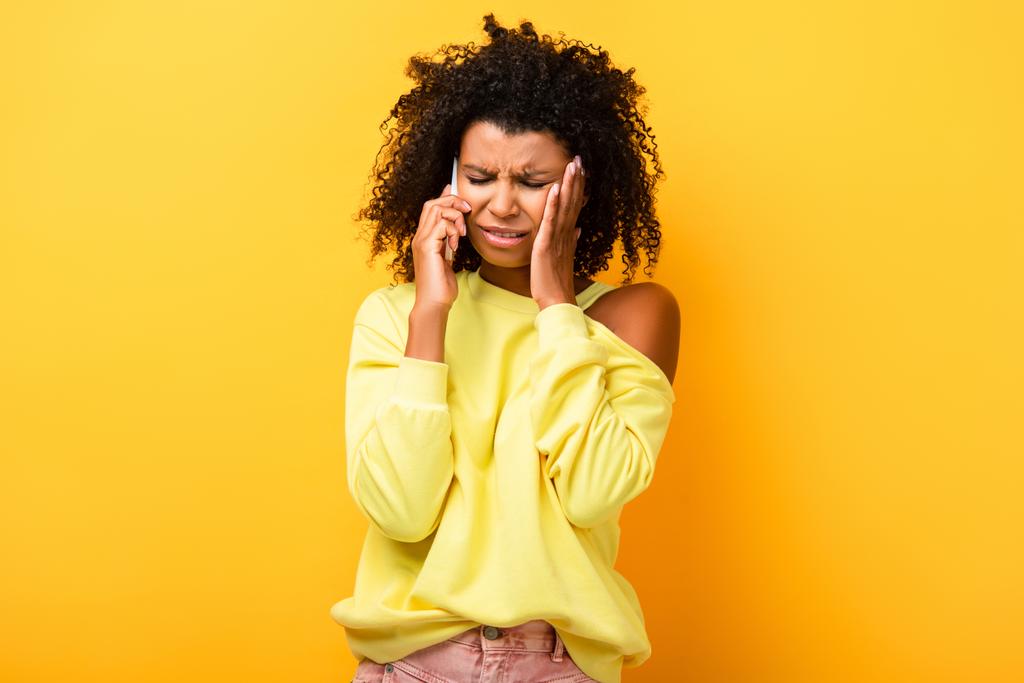 悲しいアフリカ系アメリカ人女性が黄色でスマートフォンで話しています - 写真・画像