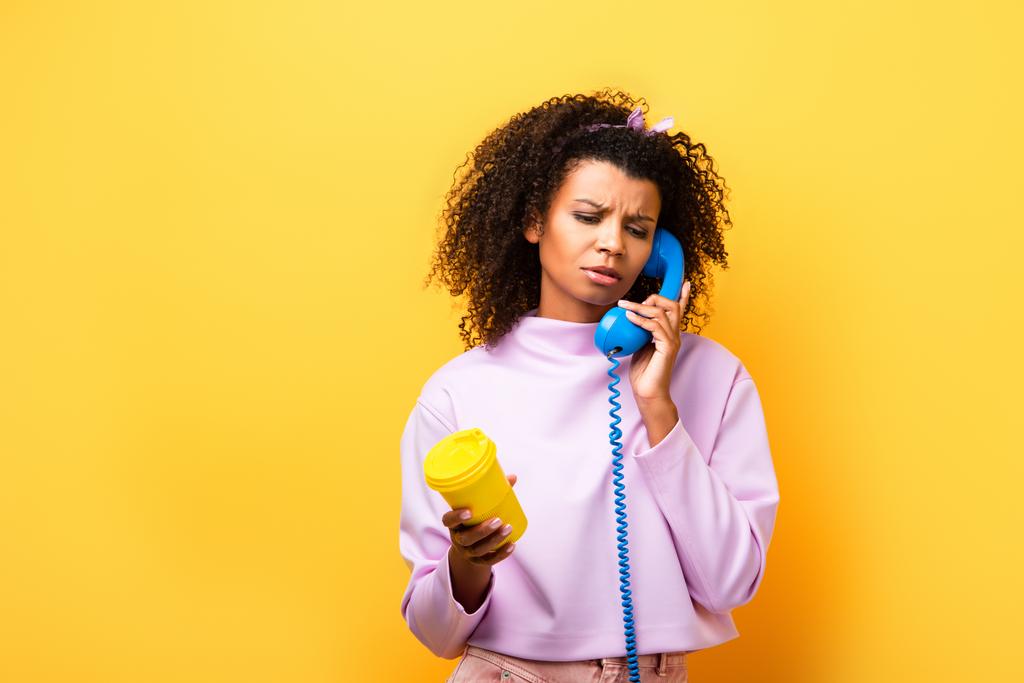 afro-amerikai nő beszél kék retro telefon és kezében ökokupa sárga - Fotó, kép