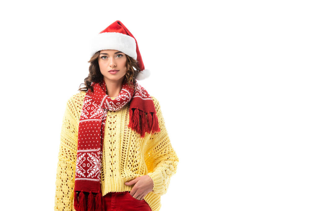 Noel Baba şapkalı ve kırmızı eşarplı genç esmer kadın elini cebine atmış, beyaz tenli.  - Fotoğraf, Görsel
