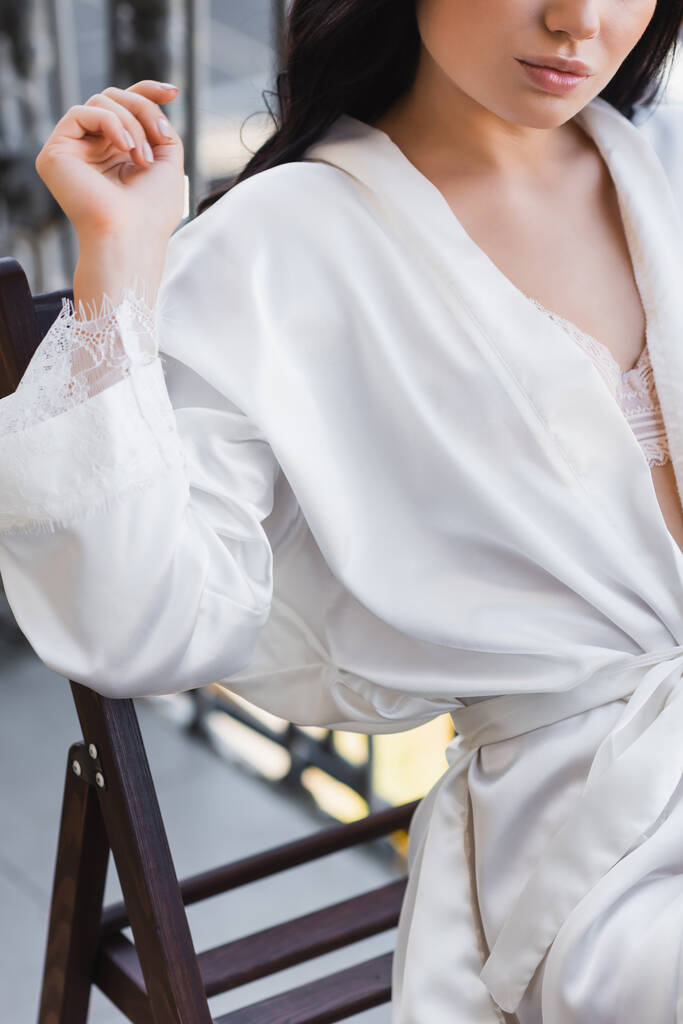 частичный вид женщины в белом халате, сидящей на стуле  - Фото, изображение