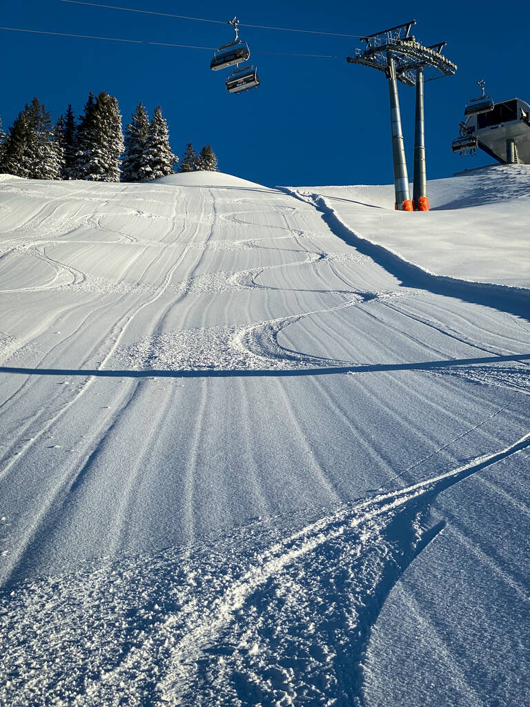 Three single traces at ski slope underneath a chairlift in the Austrian alps against blue sky - Photo, Image