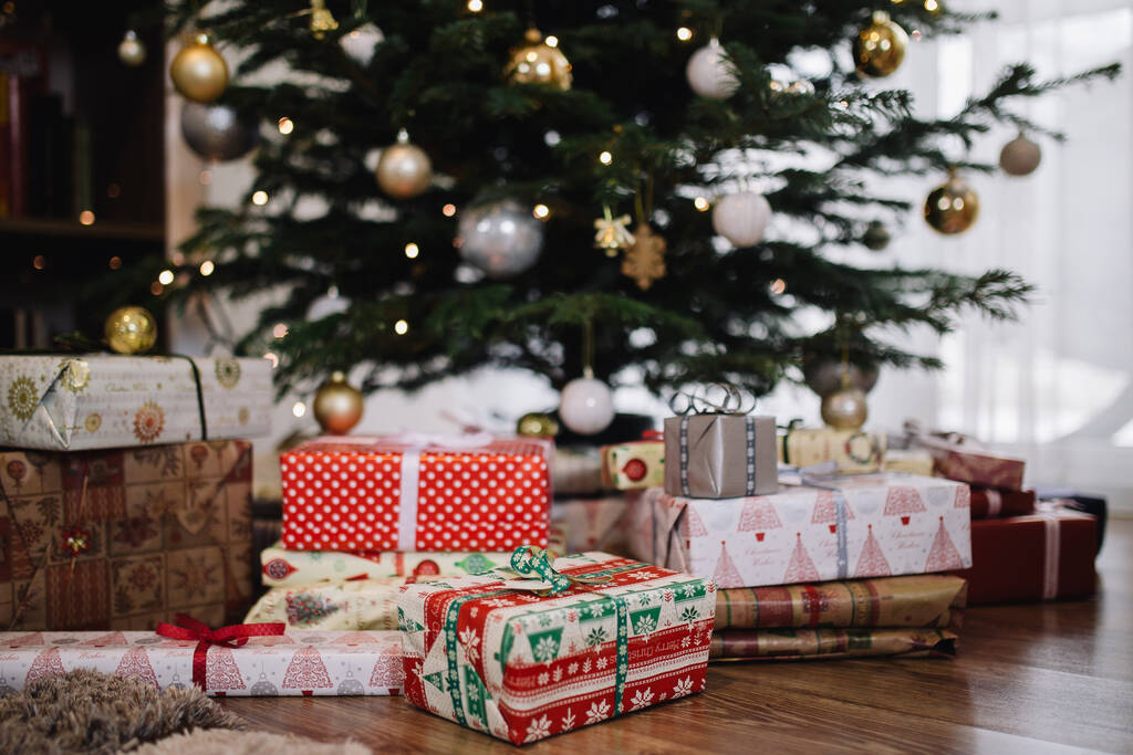 Bunte Weihnachtsgeschenke unterm Baum mit Weihnachtsbeleuchtung - Foto, Bild