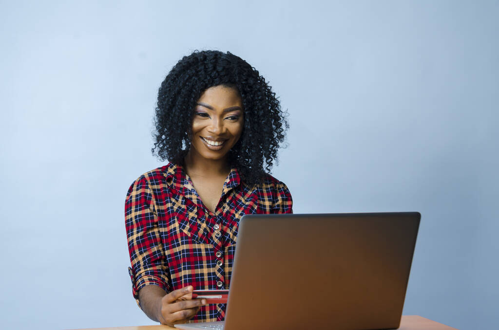 Una bella donna afro-americana seduta davanti a un computer portatile e al lavoro - Foto, immagini