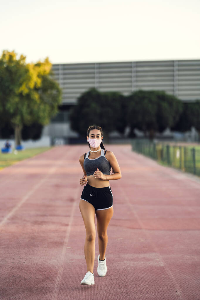 Vertikální záběr ženy v masce běžící a cvičící - Fotografie, Obrázek