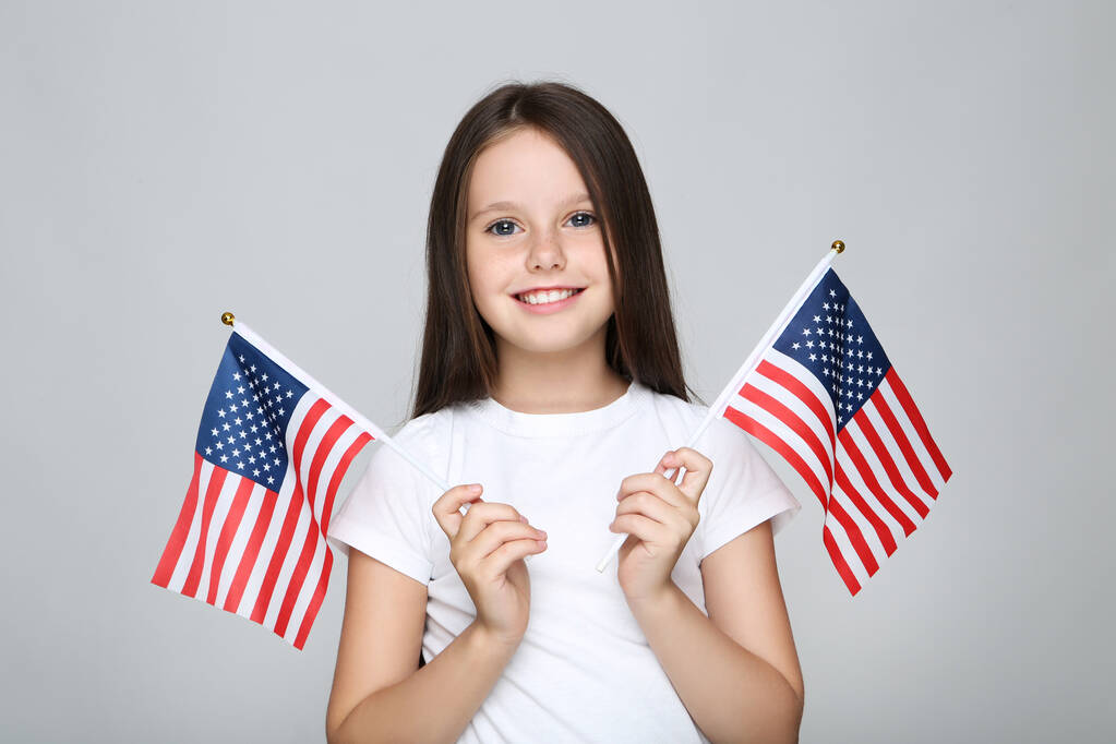Young girl holding american flags on grey background - Photo, Image
