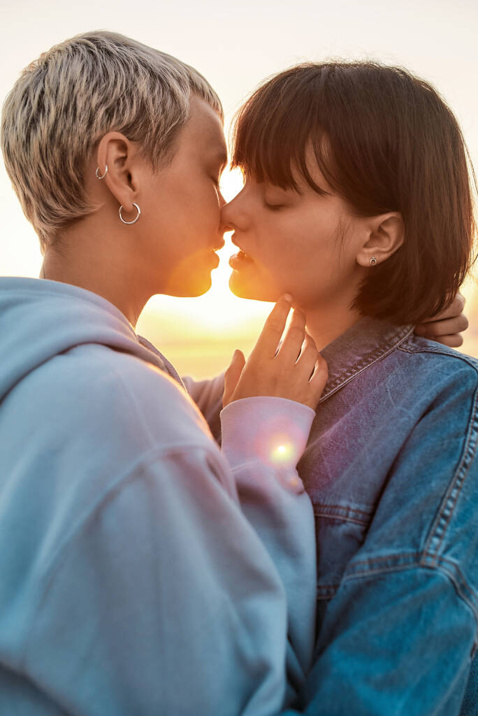 Νεαρό ζευγάρι λεσβιών που έχουν ρομαντική στιγμή, δύο γυναίκες πρόκειται να φιλήσει, ενώ βλέποντας την ανατολή του ηλίου μαζί, Επιλεκτική εστίαση - Φωτογραφία, εικόνα
