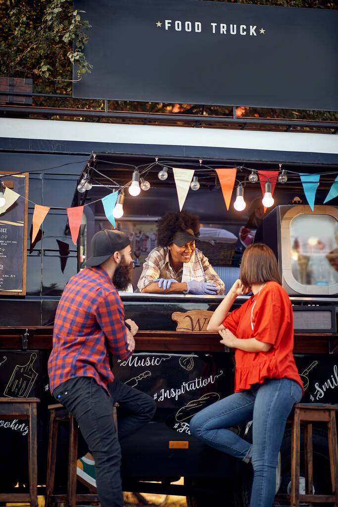 Hipster couple ordering from food truck on the street; Urban lifestyle concept - Photo, Image