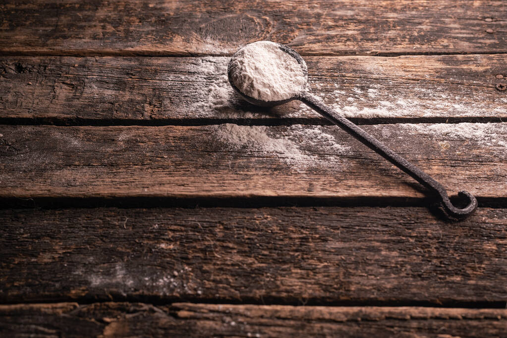 Mąka w żelaznej gałce na brązowym drewnianym tle stołu. - Zdjęcie, obraz