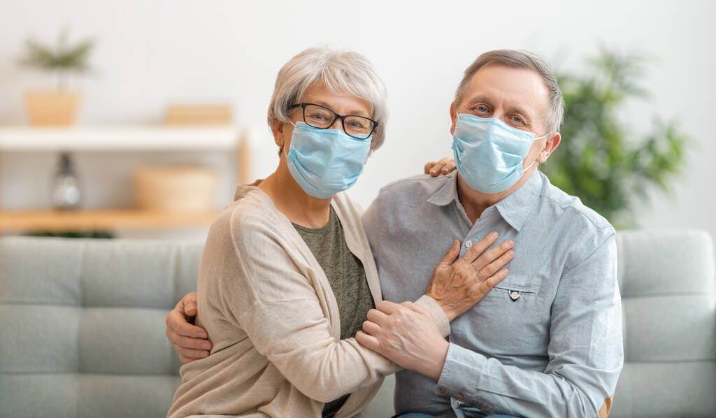 Oudere echtparen dragen gezichtsmaskers tijdens een coronavirus en griepuitbraak. Virus- en ziektebescherming, quarantaine thuis. COVID-2019. Maskers aantrekken of afdoen. - Foto, afbeelding