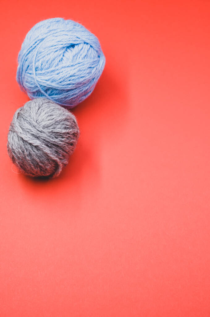A vertical shot of two balls of yarn on a red surface - Photo, Image