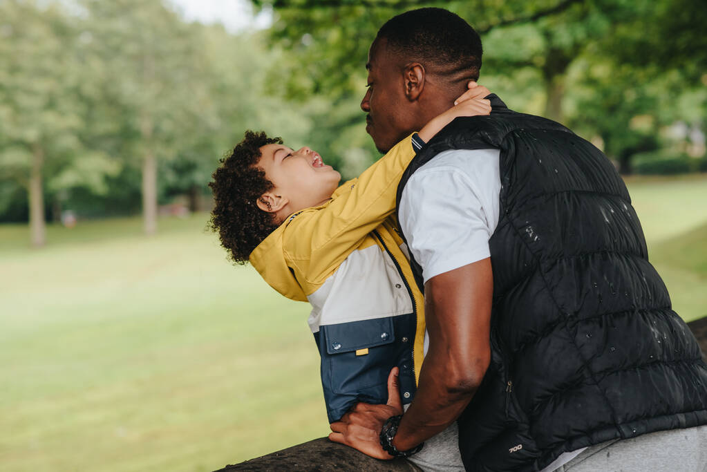 Un niño afroamericano y su padre jugando en el parque - Foto, Imagen