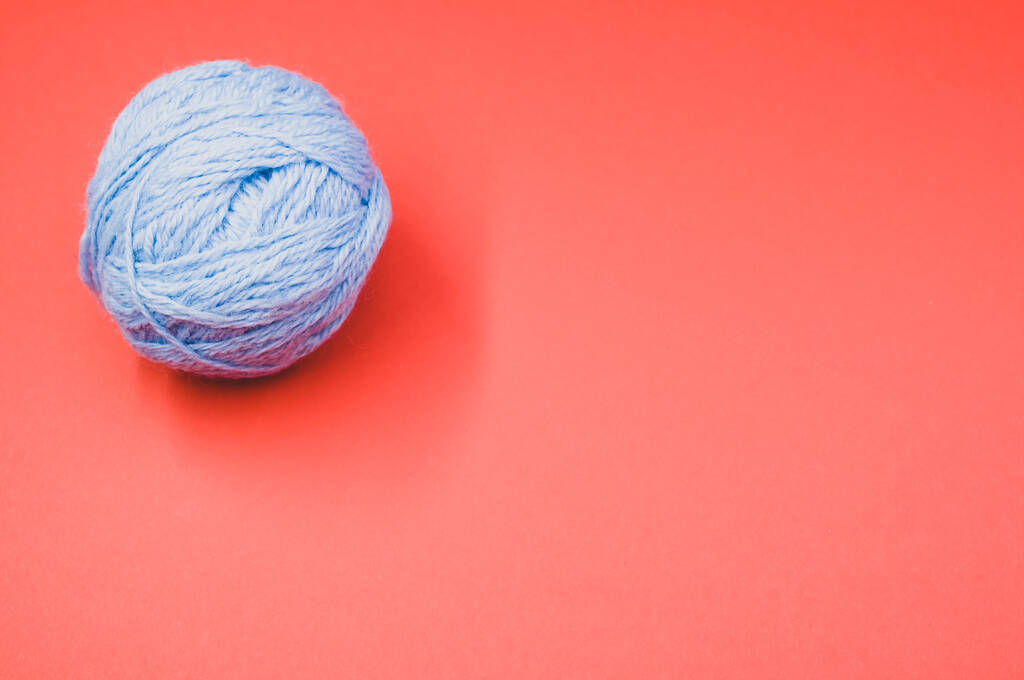 A high angle shot of a ball of yarn on a red surface - Photo, Image