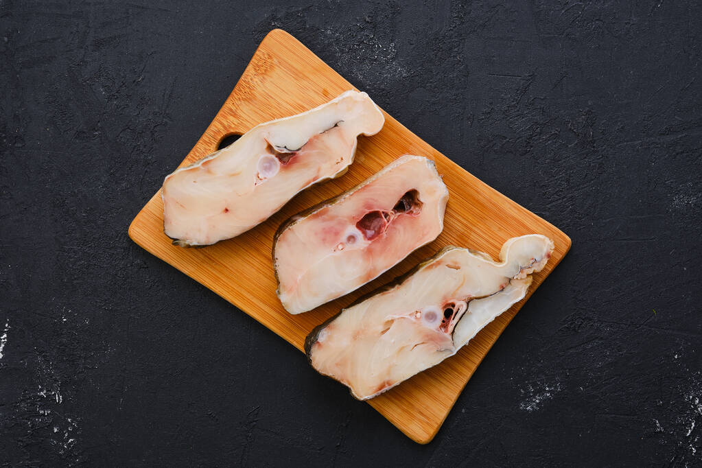 Bovenaanzicht van verse rauwe kabeljauwbiefstuk op houten snijplank met specerij - Foto, afbeelding