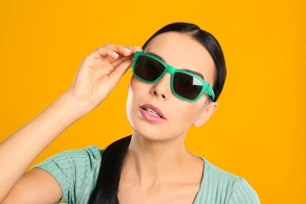 Gyönyörű nő visel napszemüveg sárga háttér, közelkép - Fotó, kép