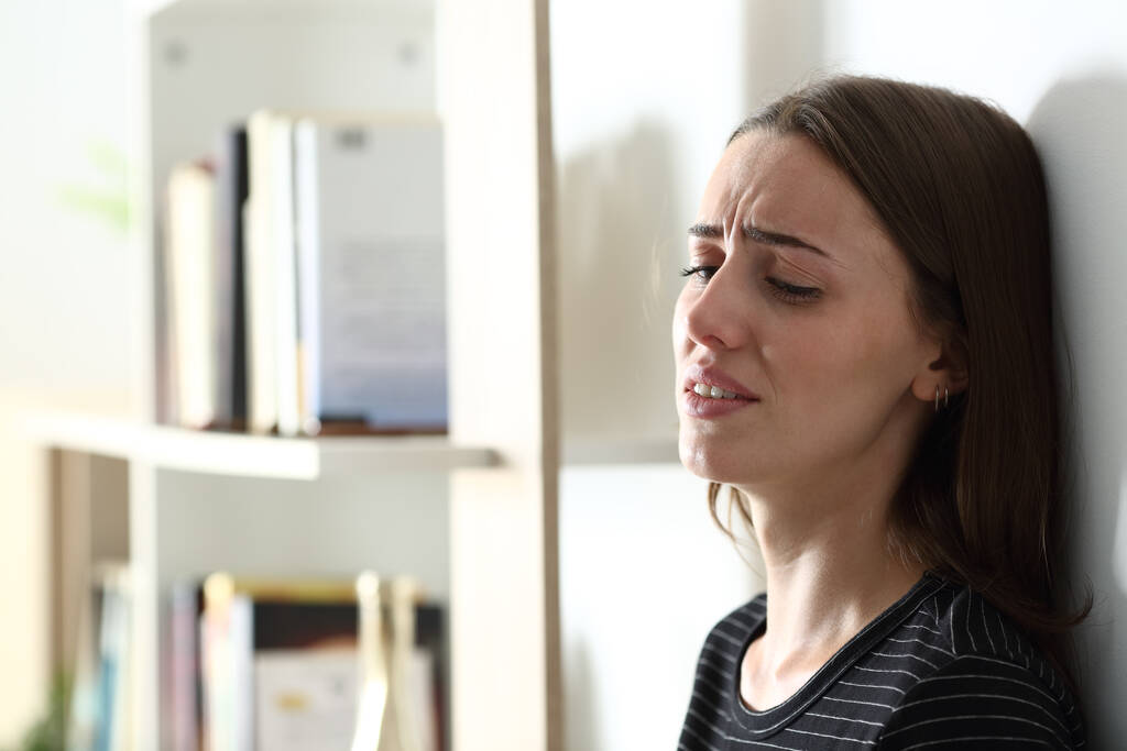 Депресивна жінка плаче сама, спираючись на стіну вдома
 - Фото, зображення