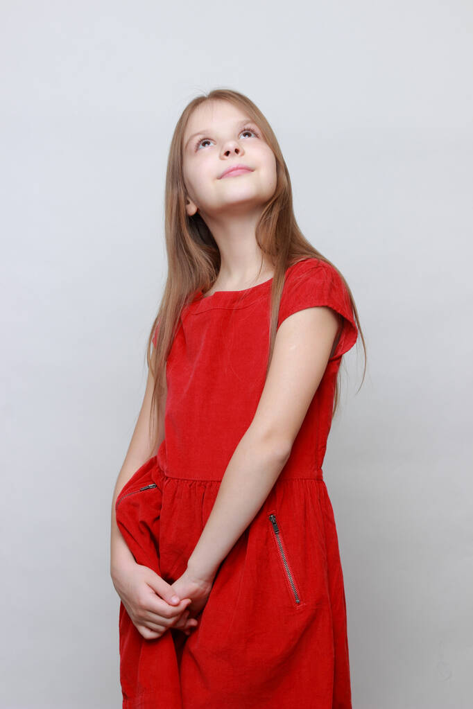Emotional kid is posing and dancing on a camera. Little girl ia a red dress. - Photo, Image