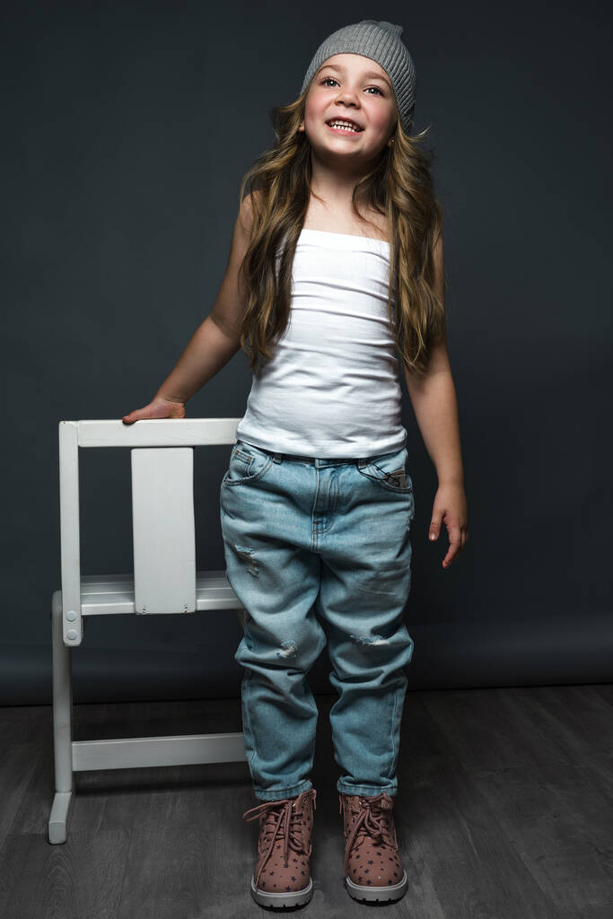 Модель маленької дівчинки професійно позує в студії в джинсах і білій футболці. Модельні тести
 - Фото, зображення