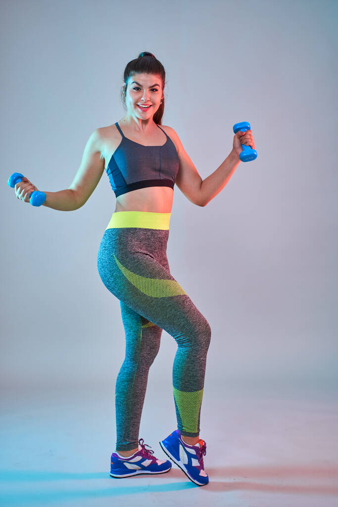 Plus size zelfverzekerde mooie jonge vrouw doet fitness oefeningen, blauw-rode toning, studio shot - Foto, afbeelding