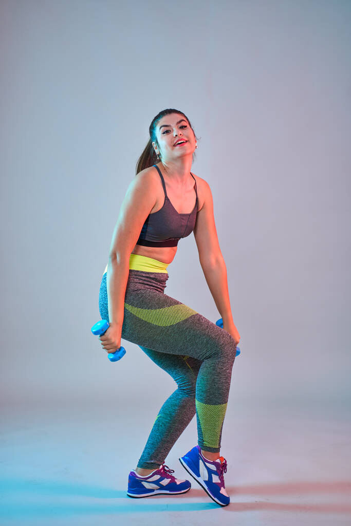 Plus la taille confiant belle jeune femme faisant des exercices de remise en forme, bleu-rouge tonifiant, plan studio - Photo, image