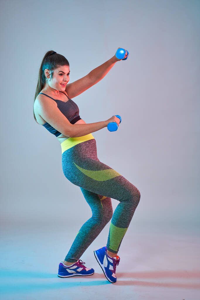 Plus size confident beautiful young woman doing fitness exercises, blue-red toning, studio shot - Photo, Image