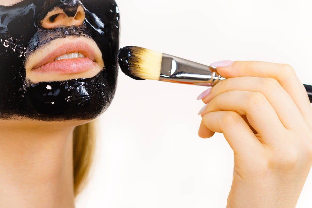 Jovem aplicando com escova preto desintoxicação descascar máscara para o rosto. Menina cuidando da pele. Tratamento de beleza. Tratamento da pele. - Foto, Imagem
