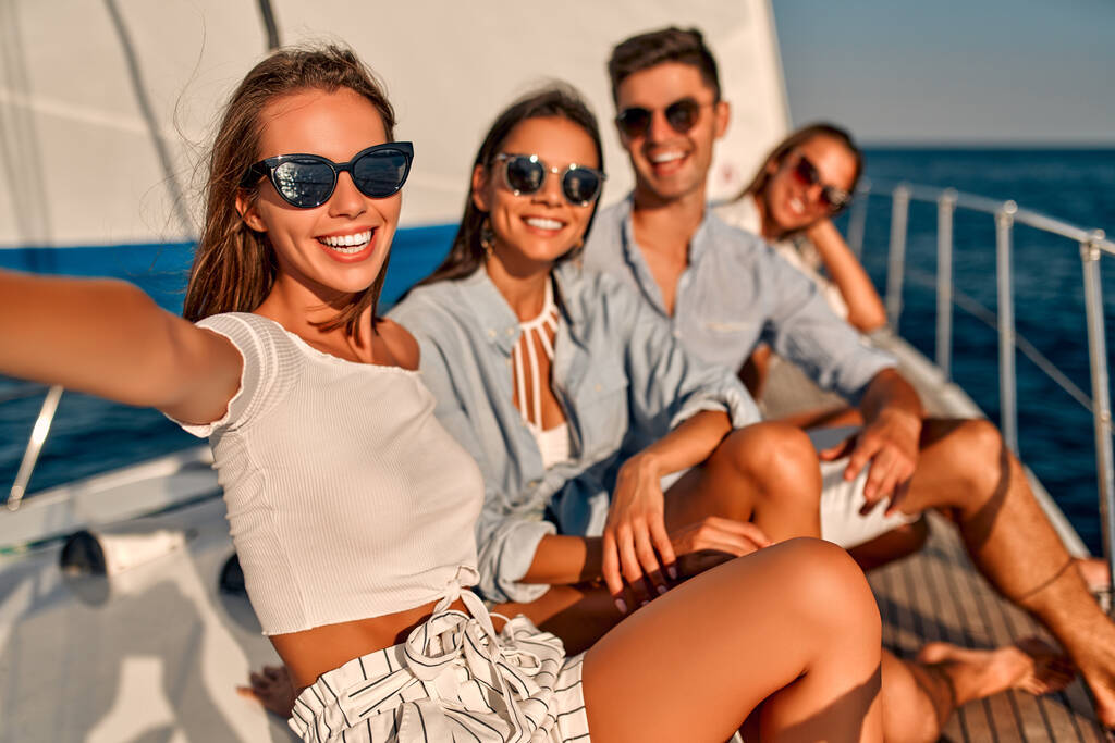 Vriendengroep ontspannen op luxe jacht. Samen plezier hebben en selfie maken tijdens het zeilen in de zee. Reis- en zeilconcept. - Foto, afbeelding