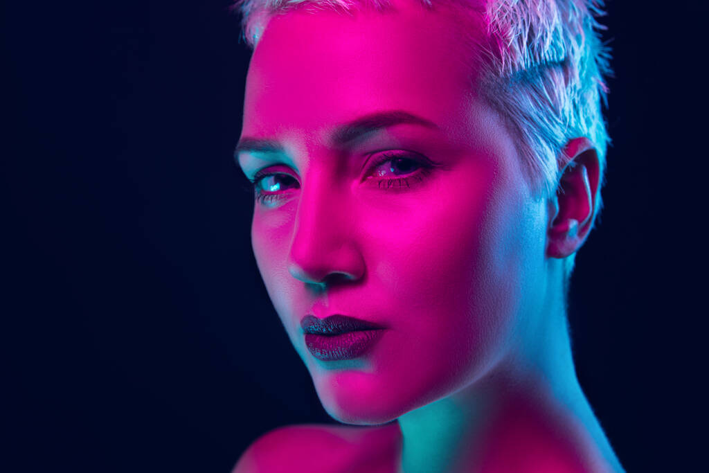 Porträt eines weiblichen Modells in Neonlicht auf dunklem Studiohintergrund. - Foto, Bild