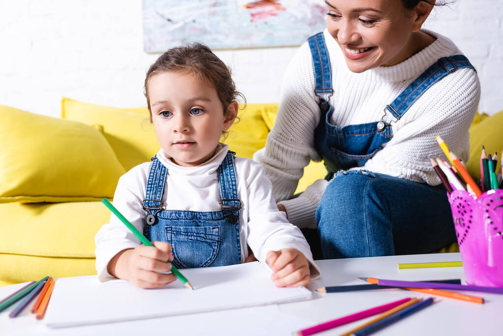 Dochter tekening met kleurpotloden bij moeder thuis - Foto, afbeelding