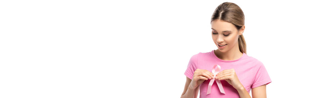 Culture horizontale de femme brune tenant un ruban rose de sensibilisation au cancer près du sein isolé sur blanc - Photo, image