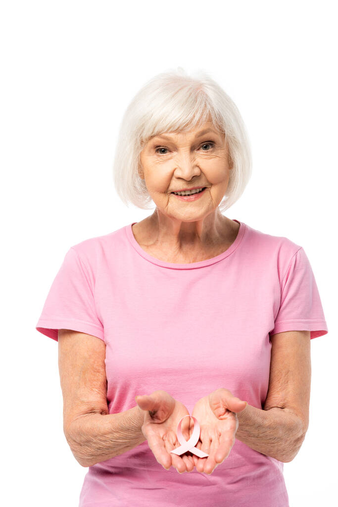 Seniorin blickt in Kamera und zeigt rosa Schleife des Brustkrebsbewusstseins - Foto, Bild