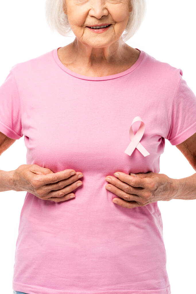 Μερική άποψη της ηλικιωμένης γυναίκας αγγίζοντας το στήθος απομονώνονται σε λευκό, έννοια του καρκίνου του μαστού  - Φωτογραφία, εικόνα