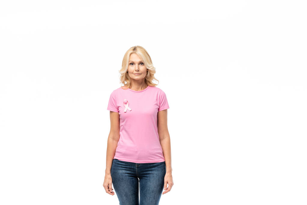 Blondynka z różową wstążką świadomości raka piersi patrząc na aparat odizolowany na białym - Zdjęcie, obraz