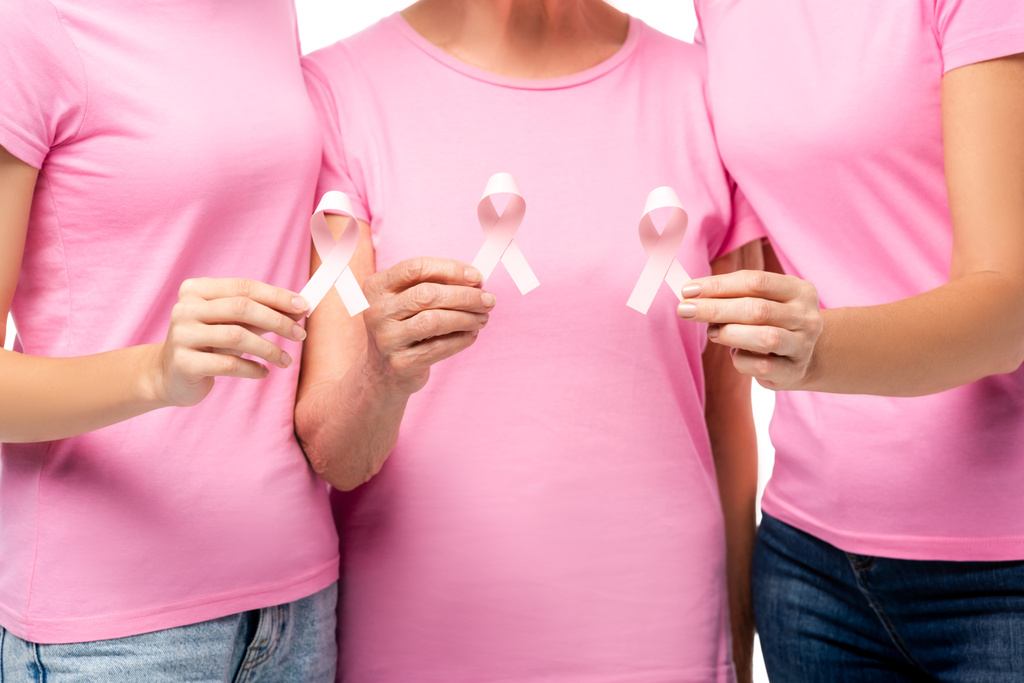 ピンクのTシャツに身を包んだ女性の乳がんに対する意識のリボンが白で孤立していることを示す - 写真・画像